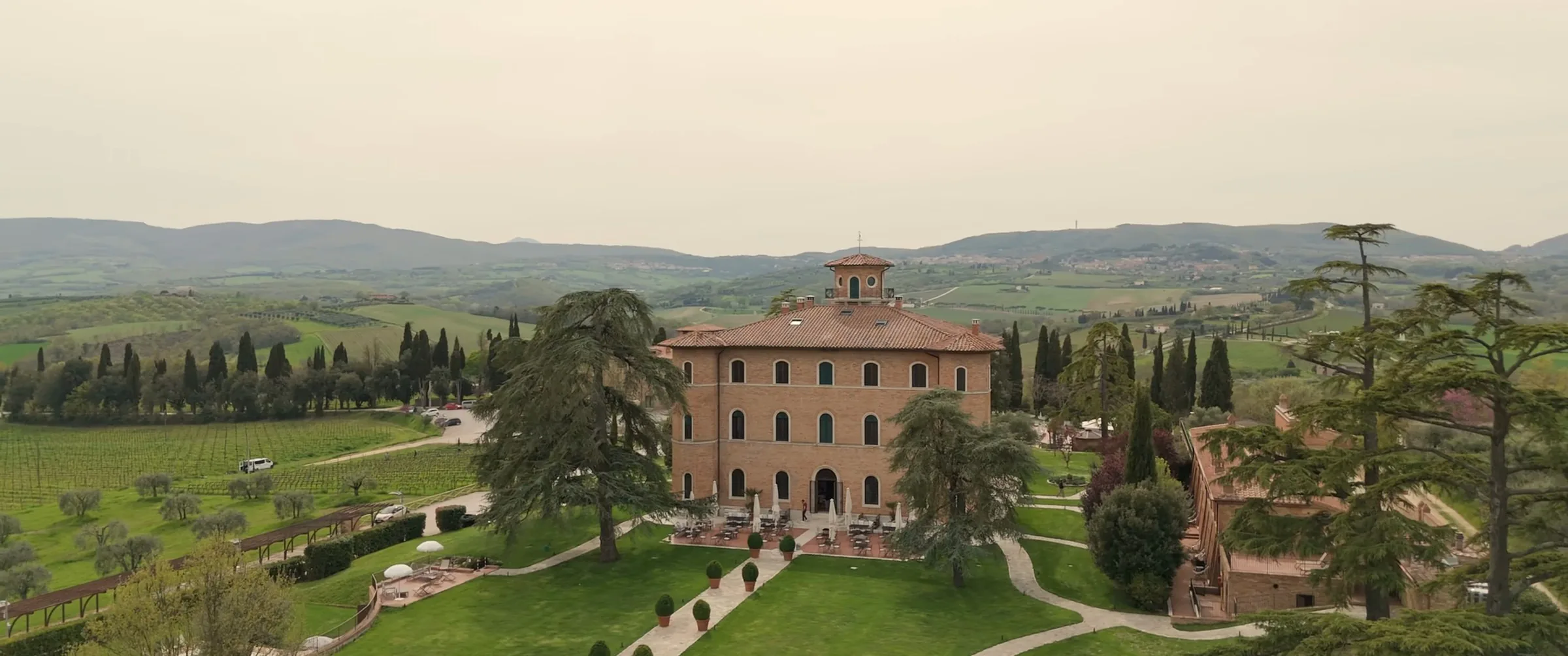 La villa in mattoni di Poggio alla Sala tra giardini, cipressi e vigneti, ripresa dal drone, fotogramma dal film di un matrimonio cinese in Toscana