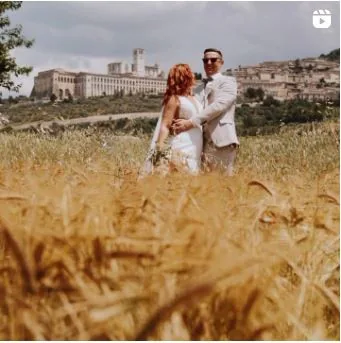 Sposi abbracciati nel grano davanti ad Assisi — reel Instagram di Cinemarry