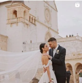 Sposi davanti alla basilica di San Francesco con il velo al vento — reel Instagram di Cinemarry