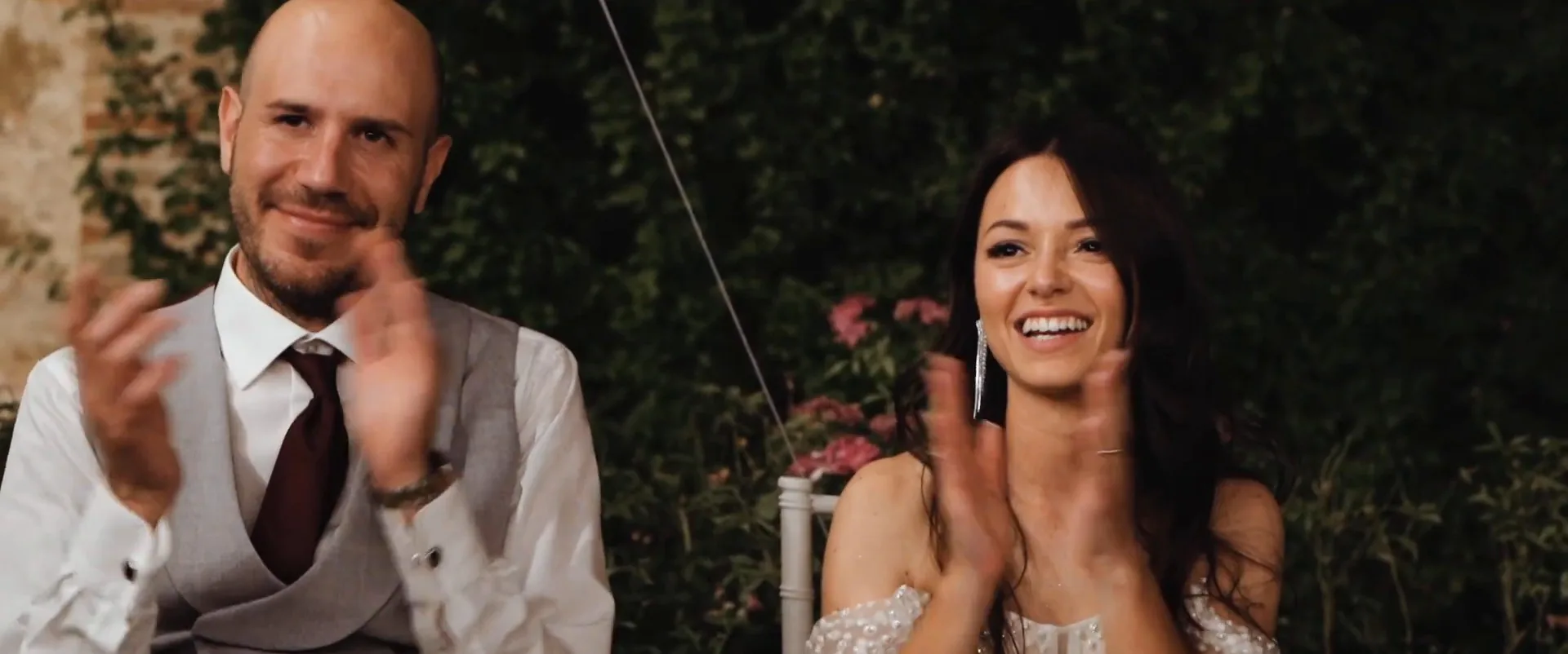 The couple applauding at the dinner table, a frame from Edoardo and Gloria’s wedding film